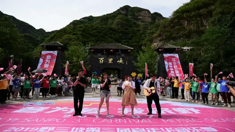 Performers outside the gates of Bailixia Canyon in Yesanpo, with green mountain slopes behind them.