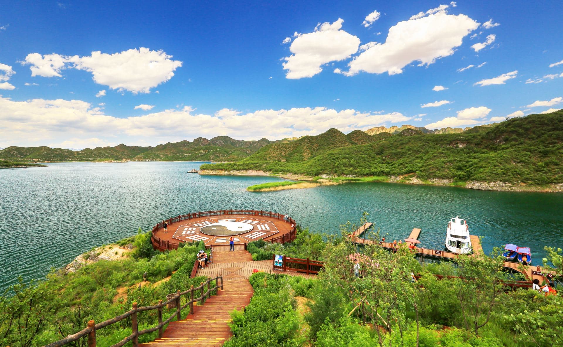 Yishui Lake with wooded hills, a wooden viewing platform and a boat at the pier